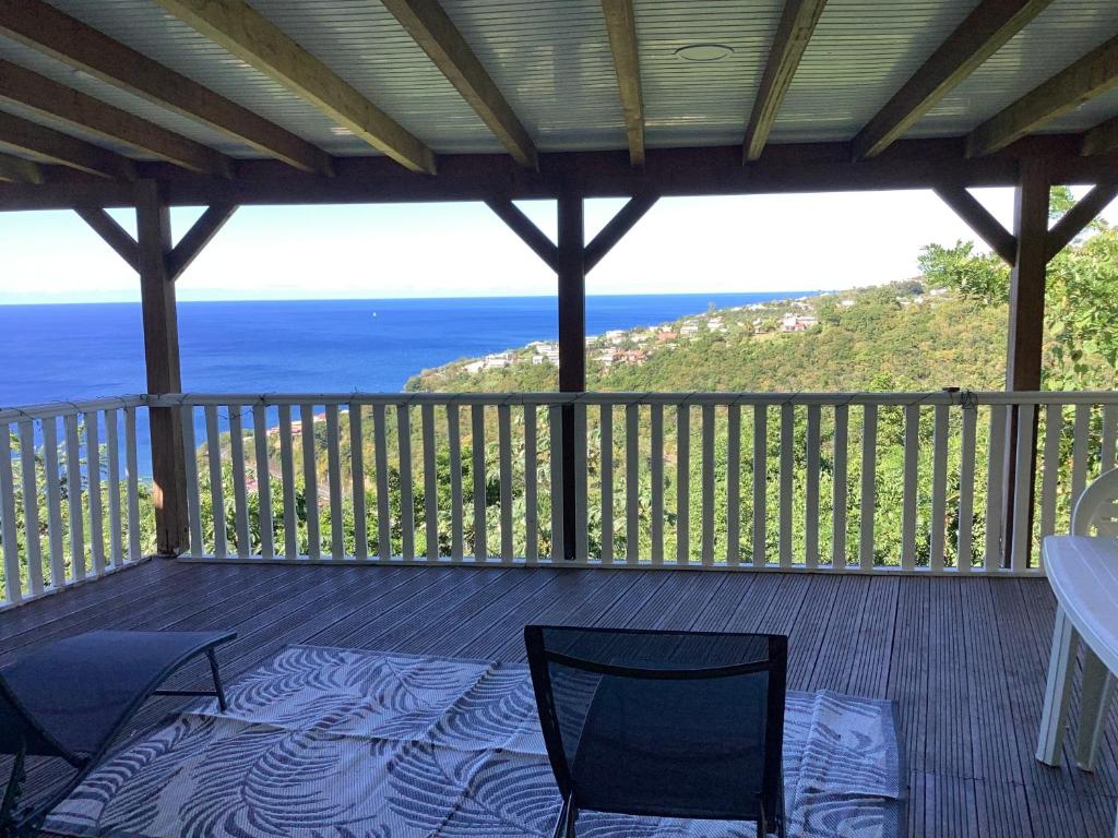 a deck with two chairs and a view of the ocean at Schoelcher : studio équipé, deck et vue imprenable in Schœlcher