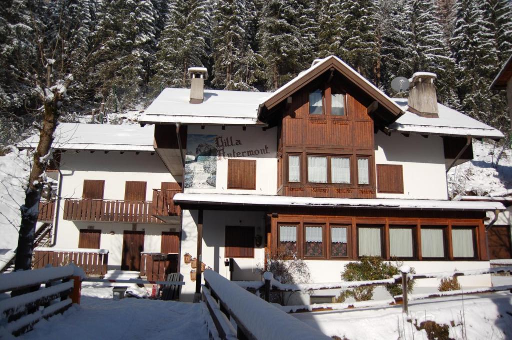 a house covered in snow in front of trees at Villa Antermont in Canazei