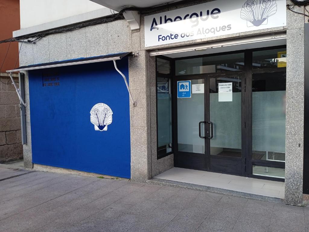 un edificio con una puerta azul con un cartel. en Fonte dos aloques, en Porriño