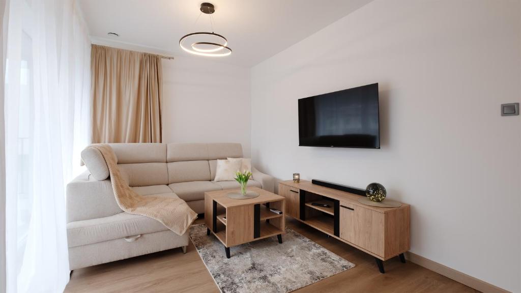 a living room with a couch and a tv at Apartamenty Sun & Snow Poniwiec in Ustroń
