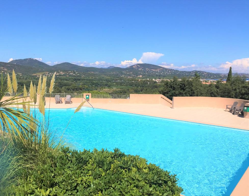 uma grande piscina azul com montanhas ao fundo em GASCOU - Golfe de St-Tropez - Mazet dans un domaine avec piscine et terrain de tennis em Cogolin
