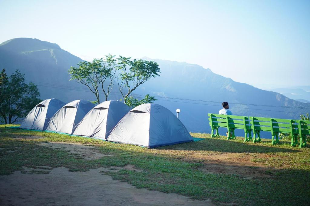 a row of tents on the grass near a body of water at Campper Eagle View Point Vagamon in Idukki