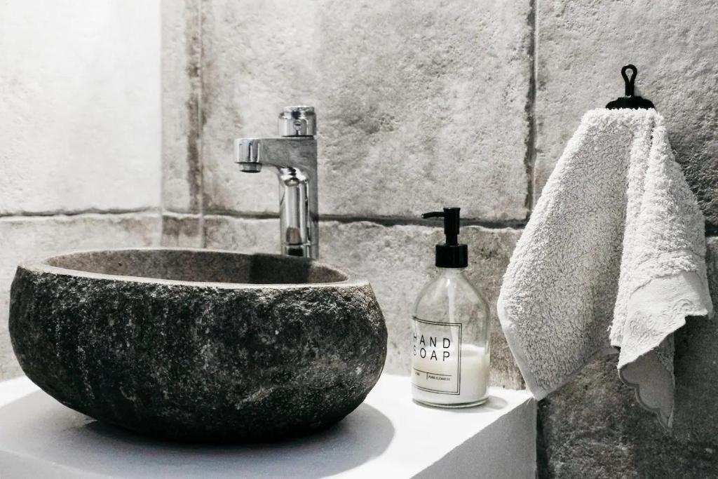 un lavabo con un gran tazón de piedra y una botella de jabón. en Zacharias Seaside Studio Kimolos, en Kimolos