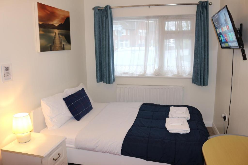 um quarto com uma cama e uma janela com uma televisão em EnSuite Room with private shower, walking distance to Harry Potter Studios em Leavesden Green