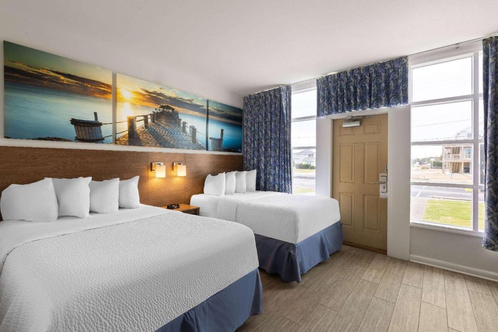 a hotel room with two beds and a window at Days Inn by Wyndham Kill Devil Hills Oceanfront - Wilbur in Kill Devil Hills