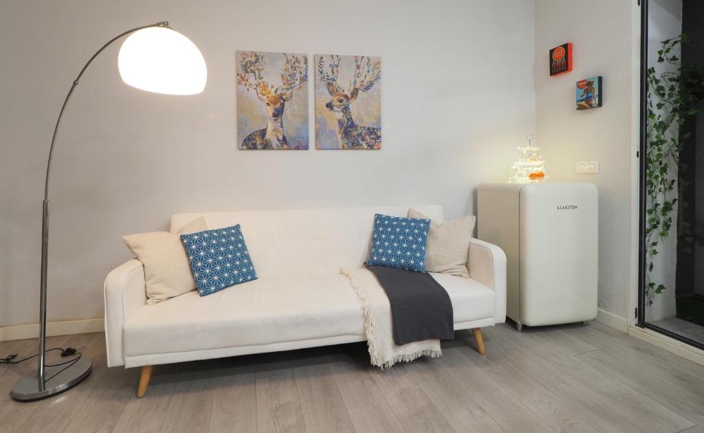 a living room with a white couch and a lamp at Tranquilidad en el corazón de Madrid. in Madrid
