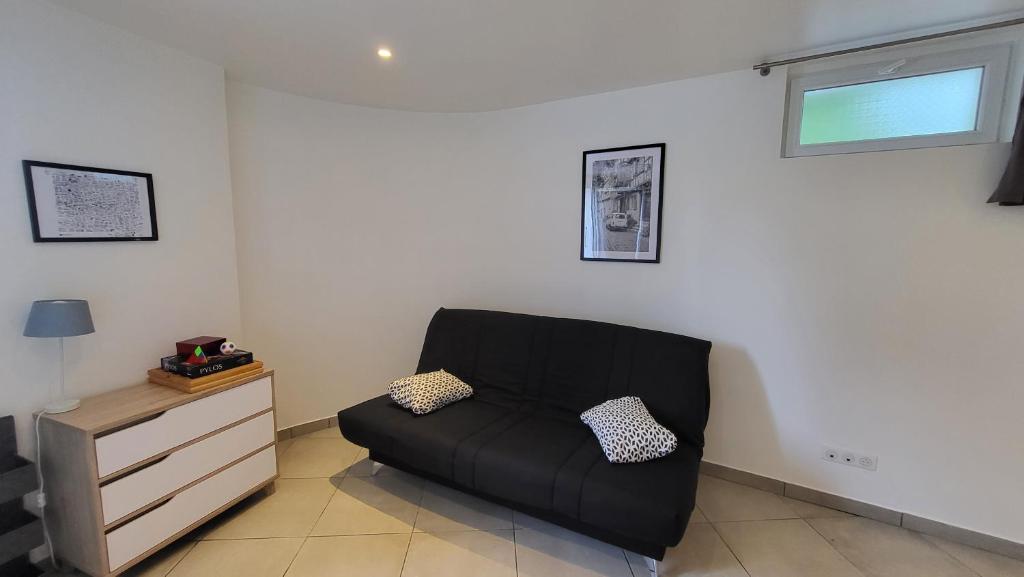 uma sala de estar com um sofá preto e uma cómoda em studio Les merles à Saint-Égrève em Saint-Égrève