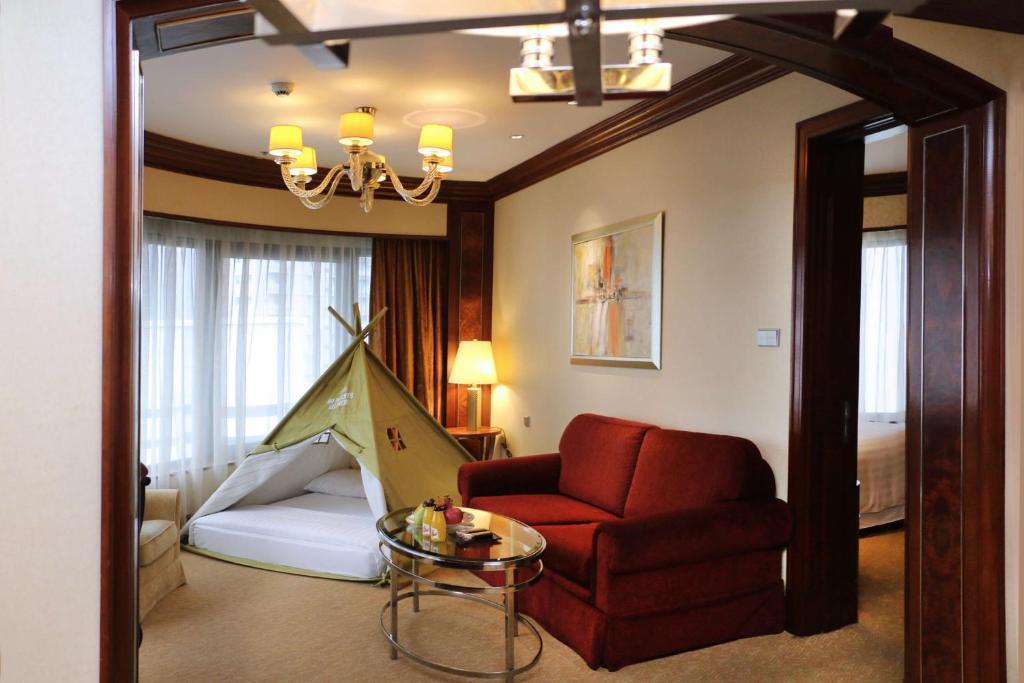 a living room with a red chair and a bed at Shangri-La Kuala Lumpur in Kuala Lumpur