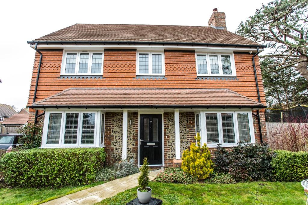 a red brick house with a black door at Pine Trees - 4 bed home in The Witterings in Chichester