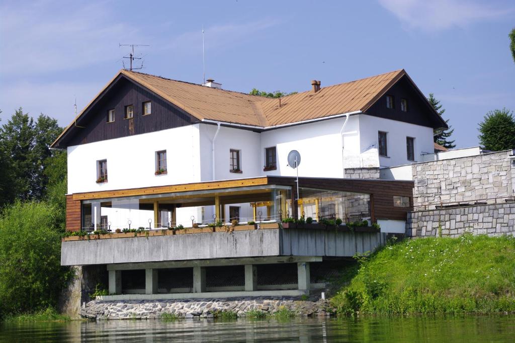 a large white house on the side of a river at Hotel Jaškovská Krčma in Horní Těrlicko