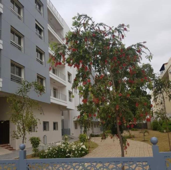 uma árvore com flores vermelhas em frente a um edifício em Appartement Résidence Panamaribo neuf em Tânger