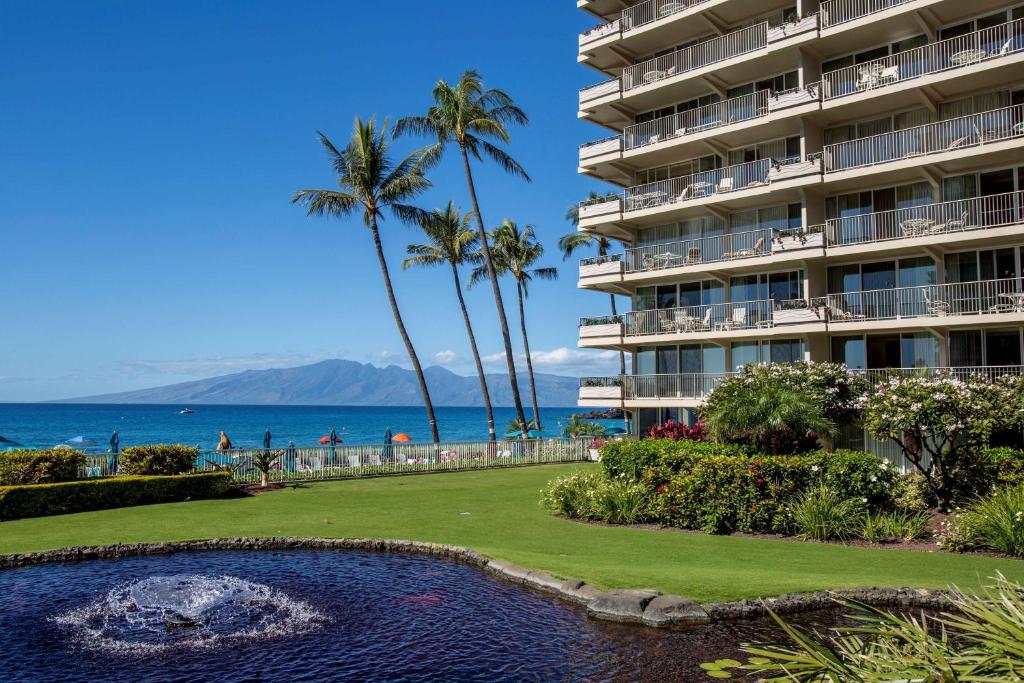 a hotel with a swimming pool and palm trees and the ocean at Aston at The Whaler on Kaanapali Beach in Lahaina