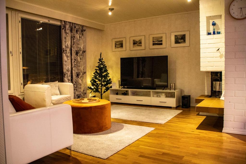 ein Wohnzimmer mit einem TV und einem Weihnachtsbaum in der Unterkunft Spacious house in Rovaniemi / Lapland (11 beds) in Rovaniemi