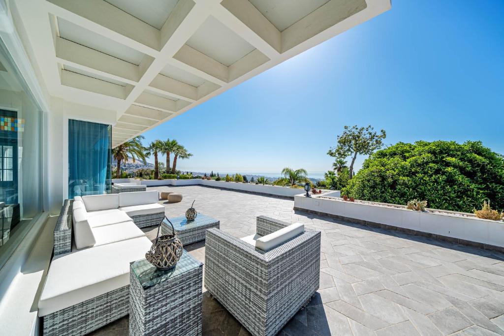 un patio esterno con mobili in vimini e l'oceano di Luxury Villa Benalmádena a Benalmádena