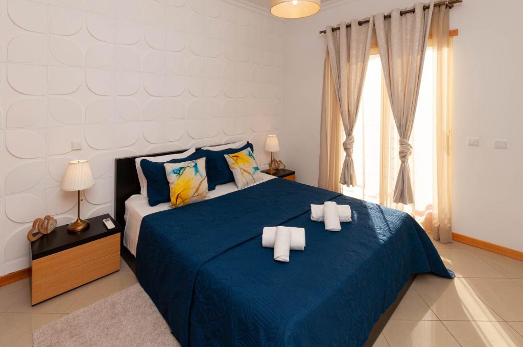 Un dormitorio con una cama azul con toallas. en Encosta da Orada by OCvillas, en Albufeira