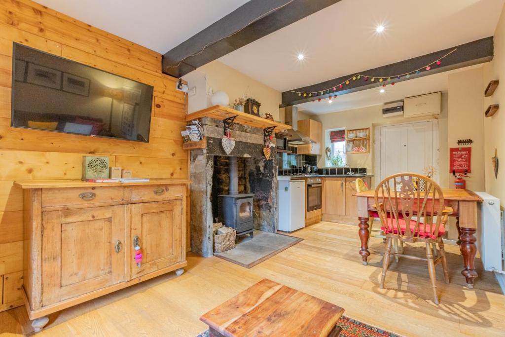 a large kitchen with a table and a fireplace at Millpond Cottage in Holmfirth