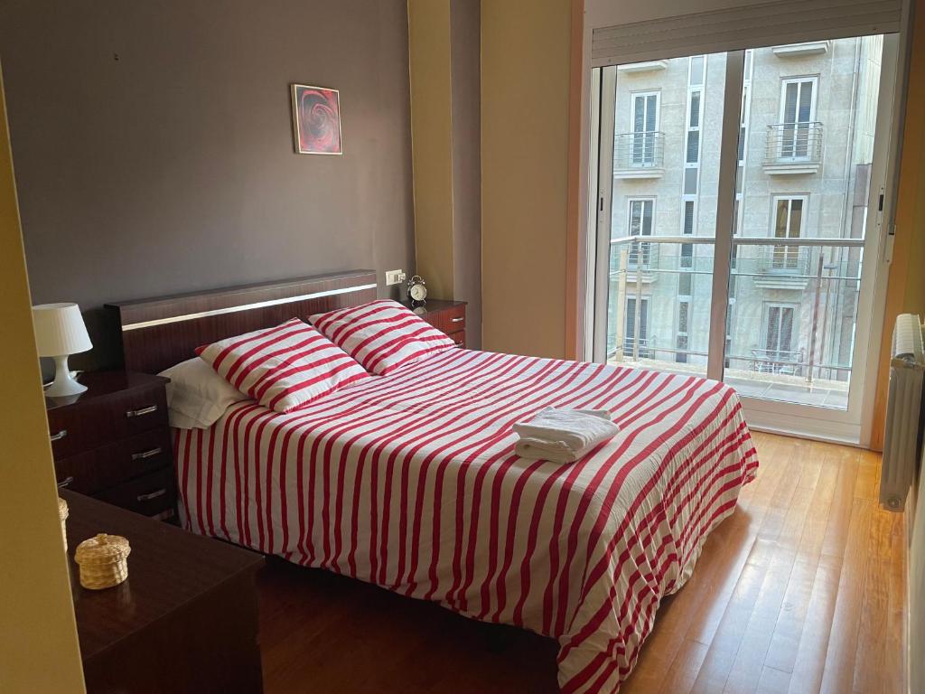 a bedroom with a bed with a red and white striped blanket at Apartamento luminoso y acogedor in Lalín
