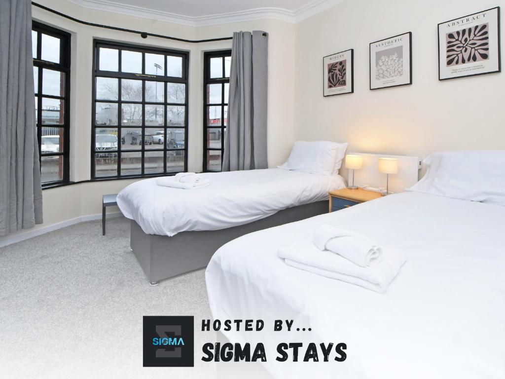 two beds in a room with two windows at Gresty House - By Sigma Stays in Crewe