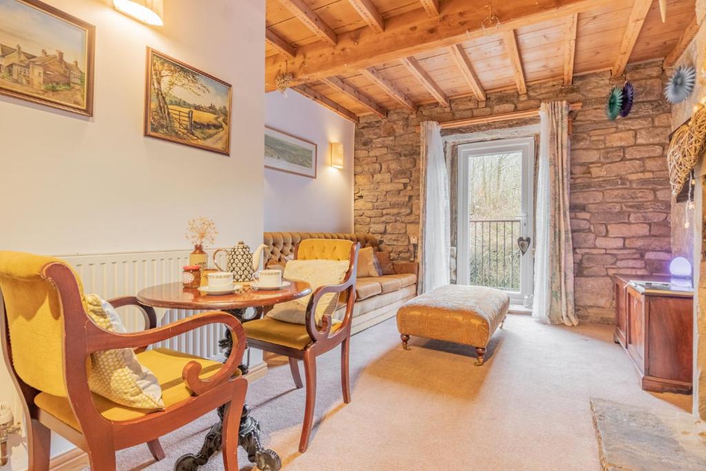 a living room with a table and chairs at Millrace Cottage in Holmfirth