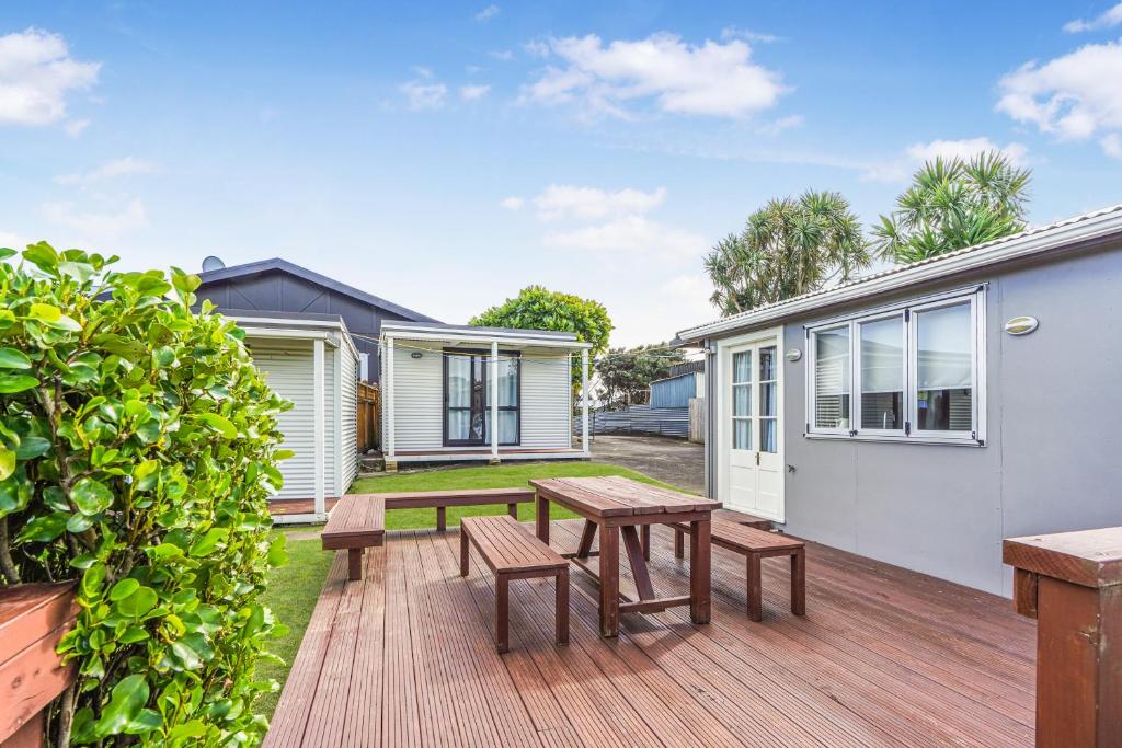 a wooden deck with a picnic table and benches at The Shed - Raglan Holiday Home in Raglan