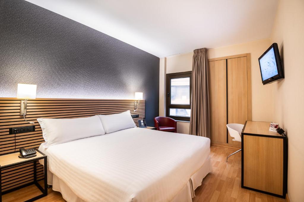um quarto de hotel com uma grande cama branca e uma janela em Civis Jaime I em Castellón de la Plana