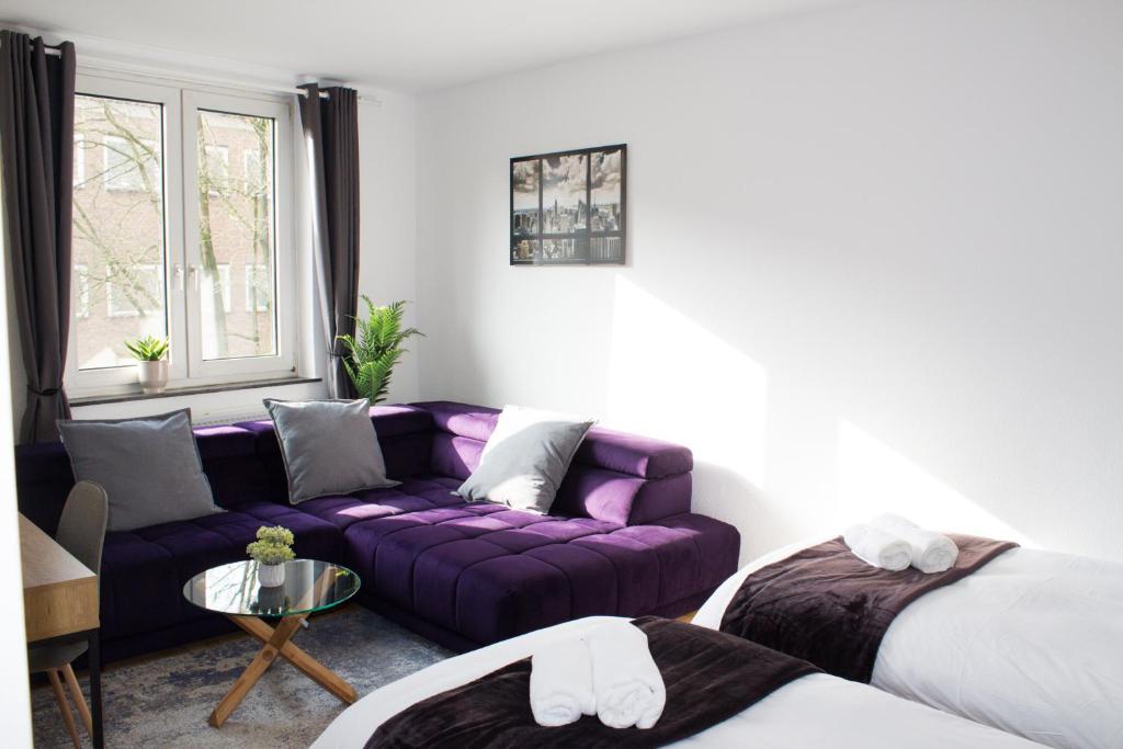 een woonkamer met een paarse bank en een tafel bij Timeless Apartment Bremen-Neustadt in Bremen