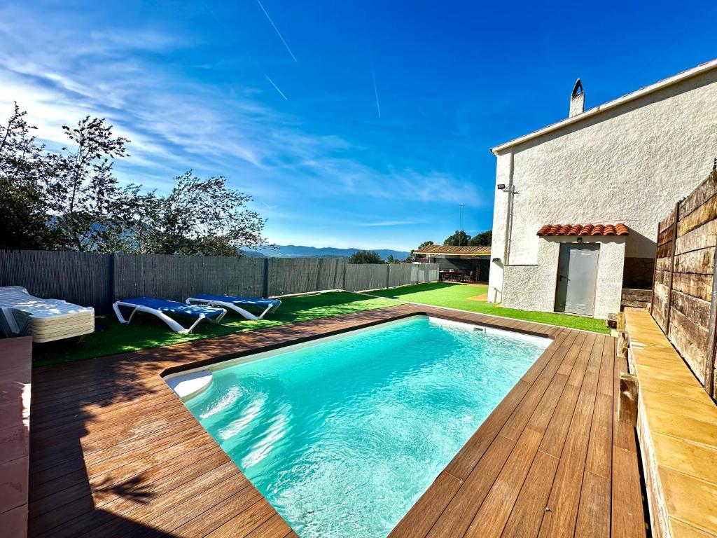 een zwembad in een achtertuin met een houten terras bij Casa MAJU in Pals