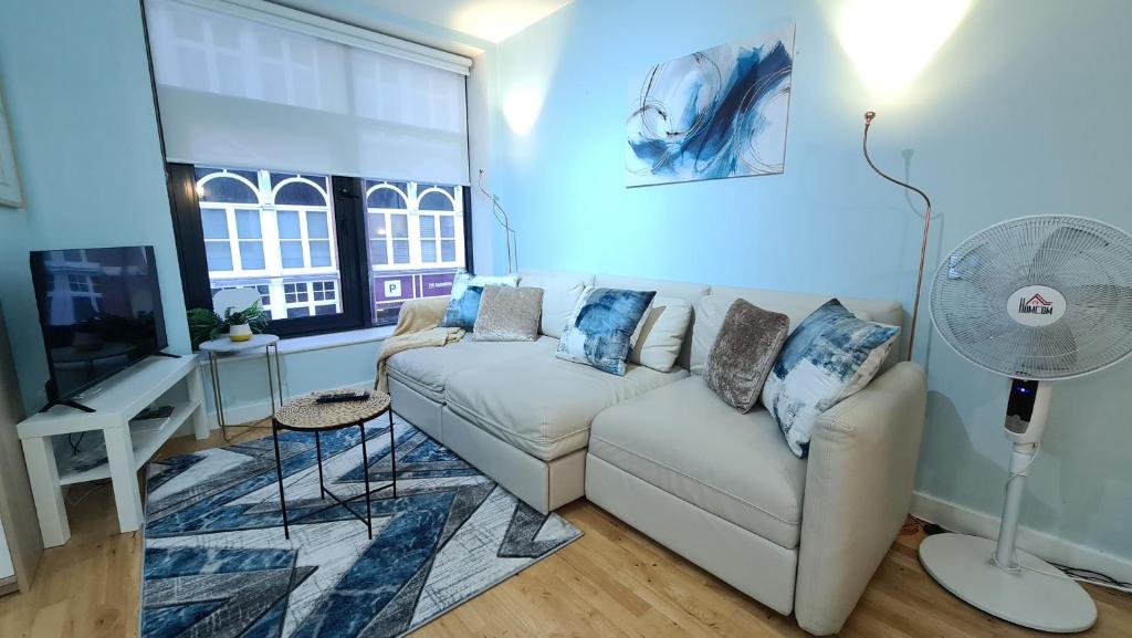 a living room with a white couch and a fan at Impressive Apartment at Leeds City Centre in Leeds