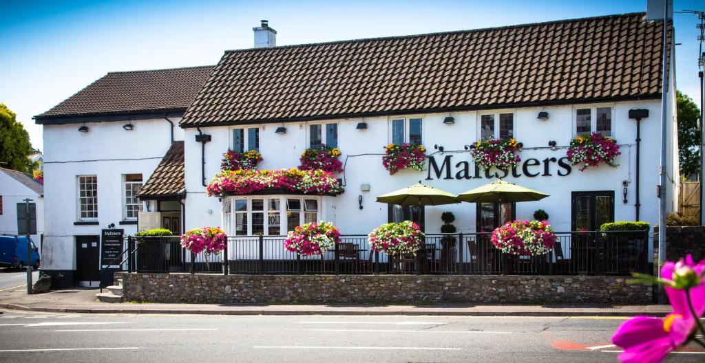 a white building with an umbrella and flowers on it at Maltsters in Cardiff