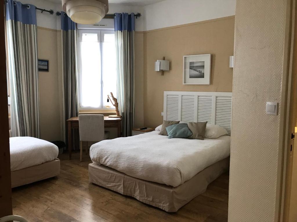1 dormitorio con 2 camas, mesa y ventana en Logis Hôtel & Restaurant "Au Gré du Vent", en Berck-sur-Mer