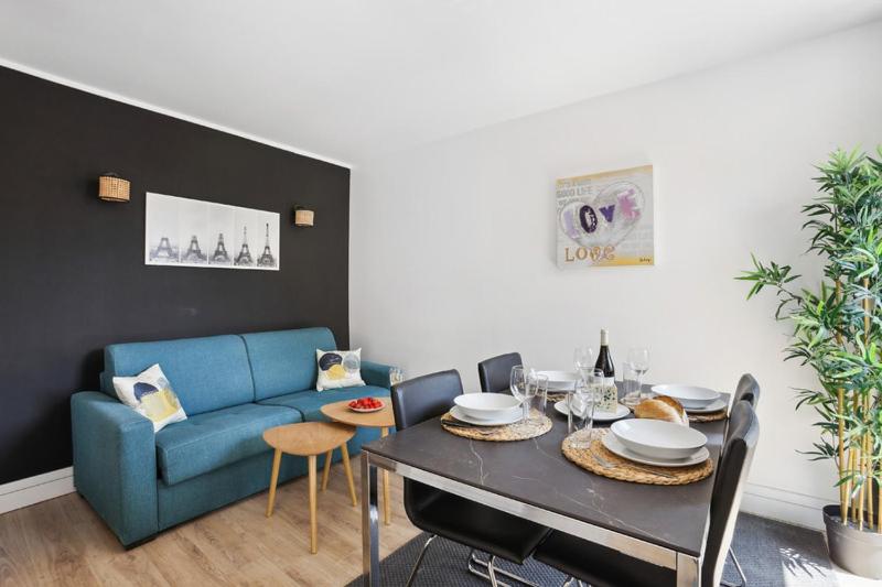 a living room with a blue couch and a table at 866 Suite Lilas - Superb apartment in Montreuil