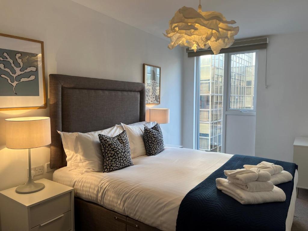 a bedroom with a large bed with towels on it at Southampton City Apartments by Charles Hope in Southampton