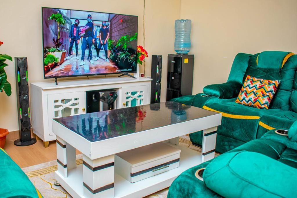 ein Wohnzimmer mit einem Sofa und einem TV in der Unterkunft Partline Apartment in Kisii