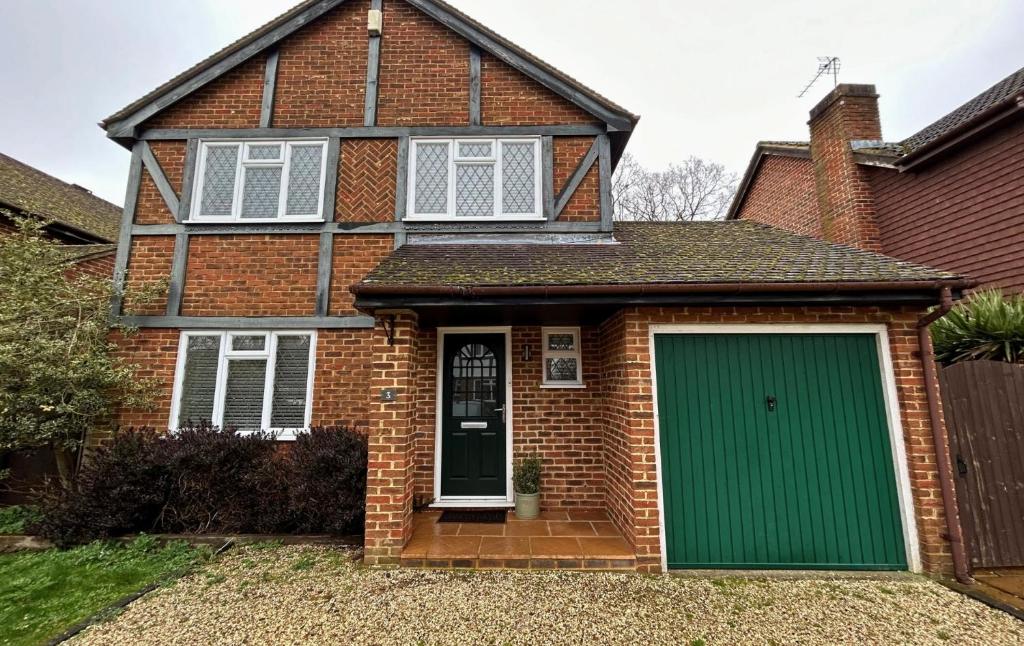 a brick house with a green garage at Binfield - Spacious Luxurious Four Bedroom House in Bracknell
