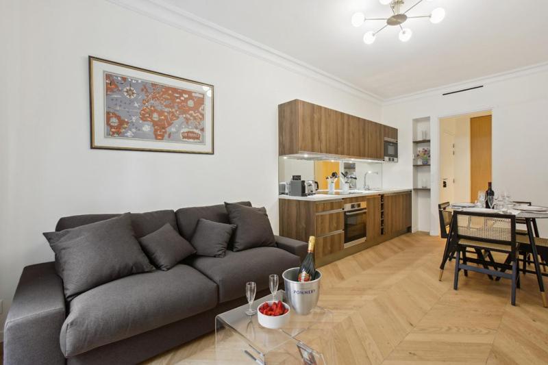 uma sala de estar com um sofá cinzento e uma cozinha em 270 Suite Haute - Superb apartment in Paris. em Paris