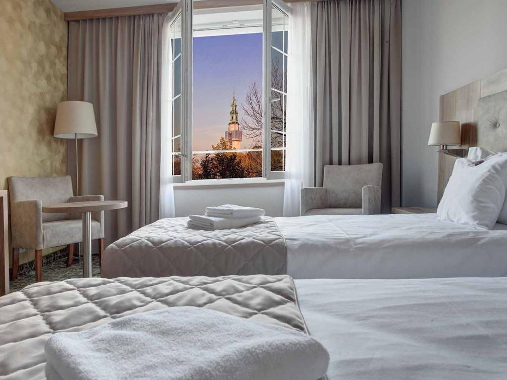チェンストホヴァにあるHotel Archeのベッド2台と大きな窓が備わるホテルルームです。