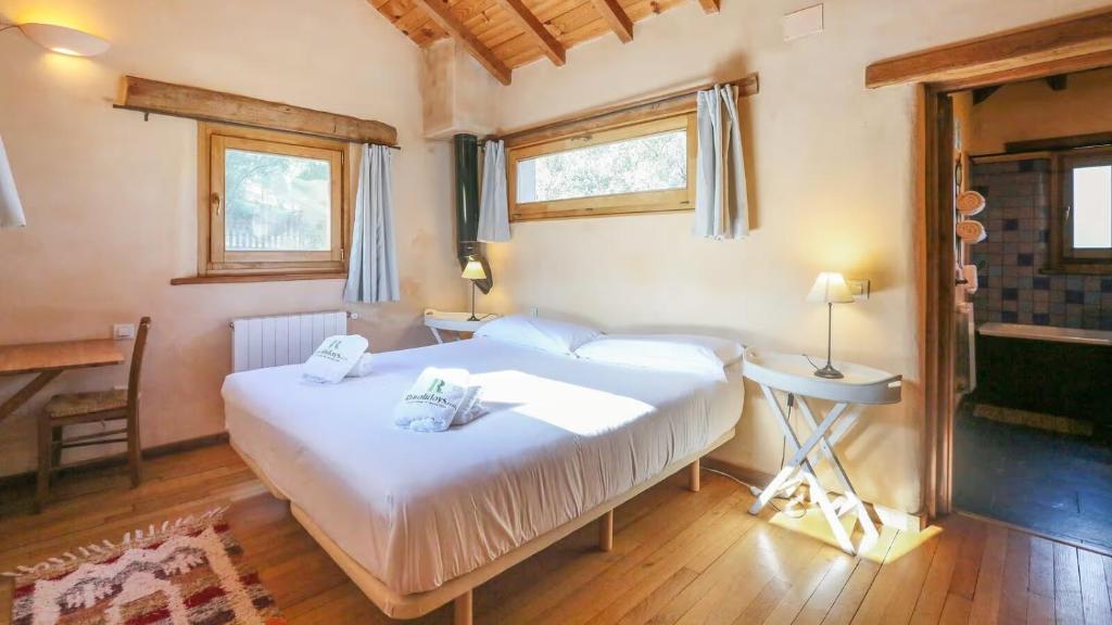 a bedroom with a large white bed and two windows at Casas Rurales Camino del Castaño in Galaroza
