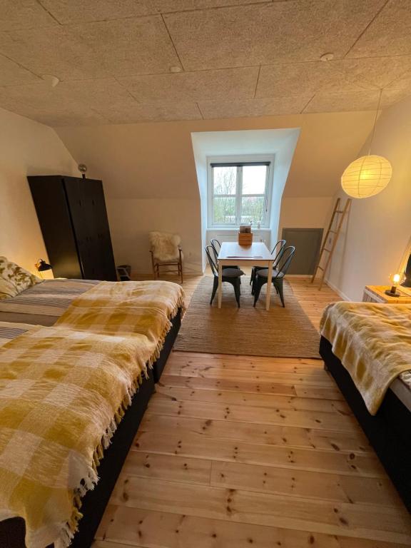 een slaapkamer met 2 bedden, een tafel en een raam bij Room 17 - Hawkraft kulturhotel in Vestervig