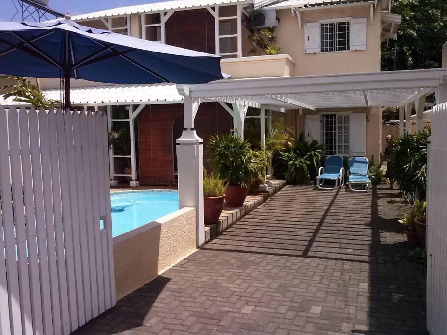 a house with an umbrella and a swimming pool at Bungalow Forgetti at Trou aux Biches with private swimming pool in Trou aux Biches