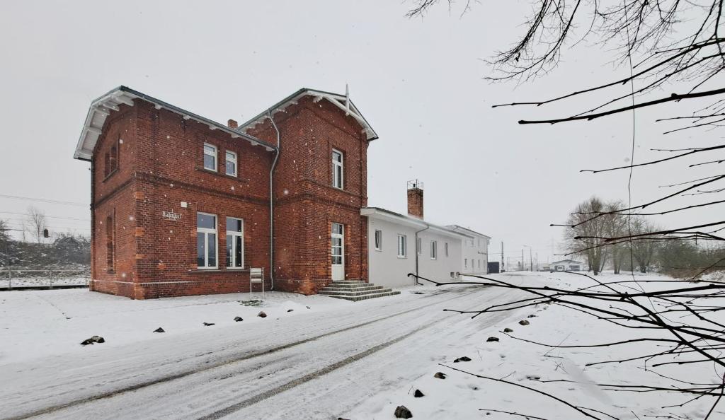 un gran edificio de ladrillo con nieve en el suelo en Pension am Bahnhof Kavelstorf, en Kavelstorf
