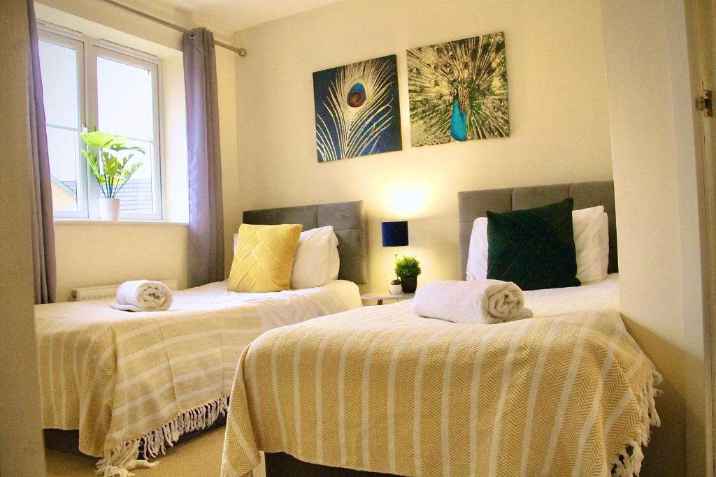 2 letti con asciugamani in una stanza di EasyRest House Peterborough - 6 Beds & Private Parking - Easy Location - Access to A1, City Centre & Shops a Peterborough