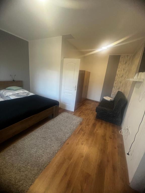 um quarto com uma cama e uma cadeira e pisos em madeira em Milan Apartman em Budapeste