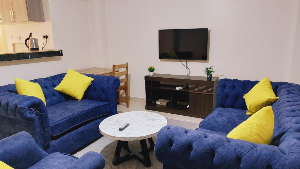 ein Wohnzimmer mit 2 blauen Sofas und einem TV in der Unterkunft MaGiK Furnished All Ensuite 2 bedroom Apartment in Nyeri