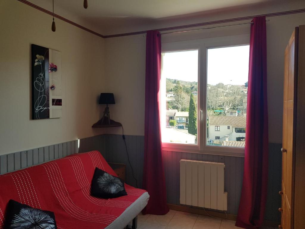 ein Wohnzimmer mit einem roten Sofa und einem Fenster in der Unterkunft Studio Albizia Lamalou les Bains in Lamalou-les-Bains