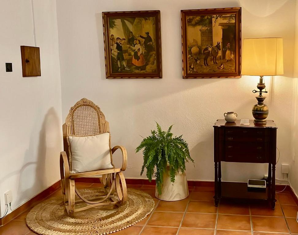 una habitación con una silla y una planta y cuadros en la pared en Casa de pueblo Ca Barret, a tan sólo dos kilómetros de Xàtiva, 