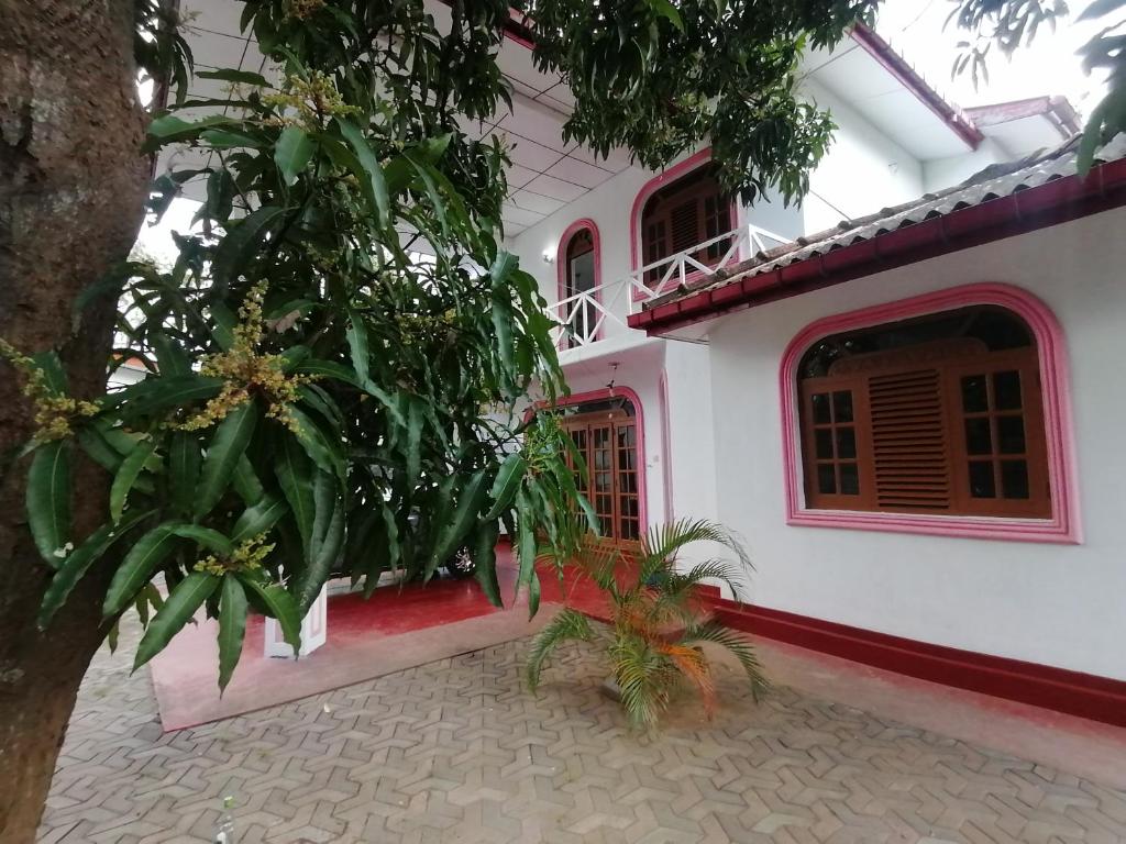 Una casa blanca con un árbol delante. en Sunshine Guest House en Polonnaruwa