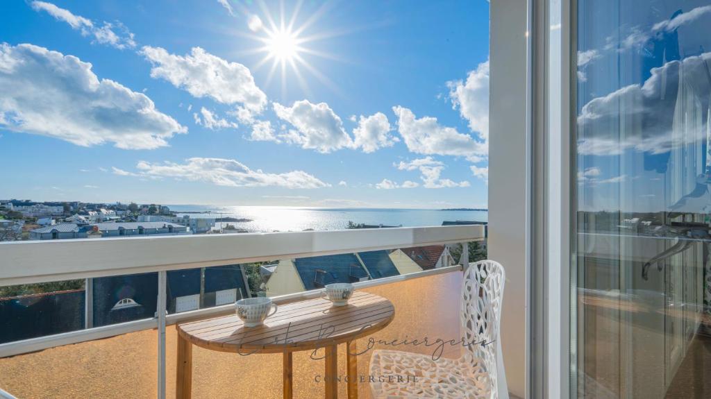 EVASION MARINE appartement VUE MER 2-4 personnes في كونكارنو: شرفة مع طاولة وإطلالة على المحيط
