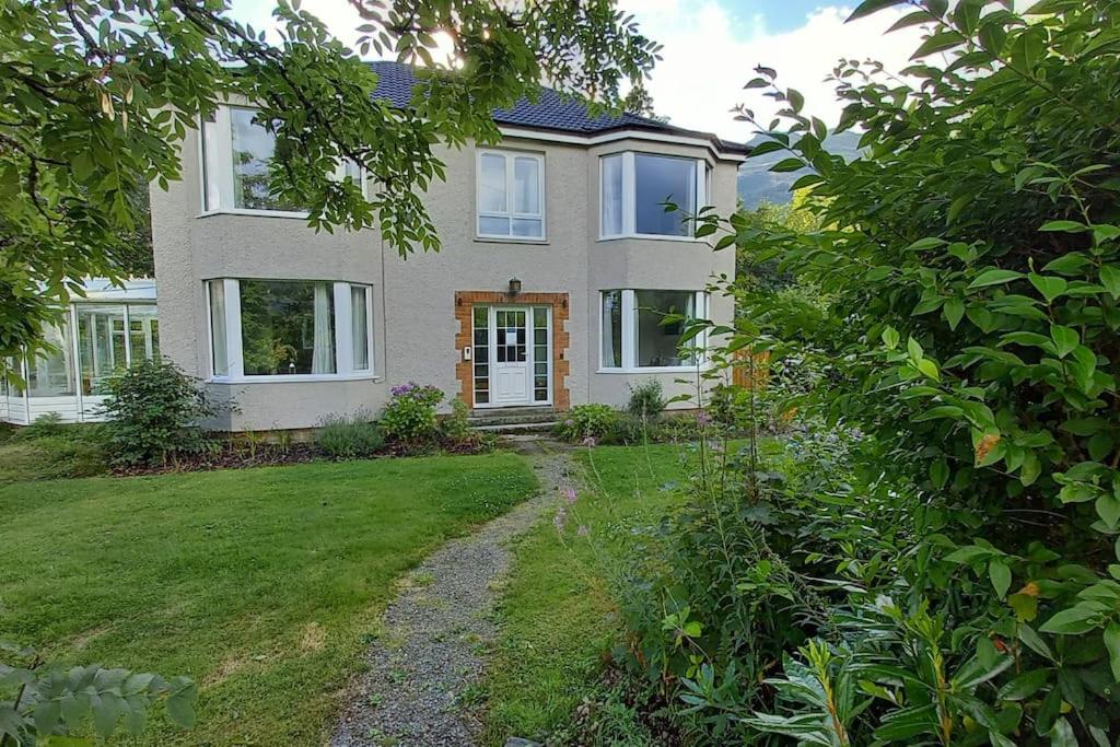 a large house with a yard with a path in front of it at Whisperwood at Carrick Castle Estate in Carrick