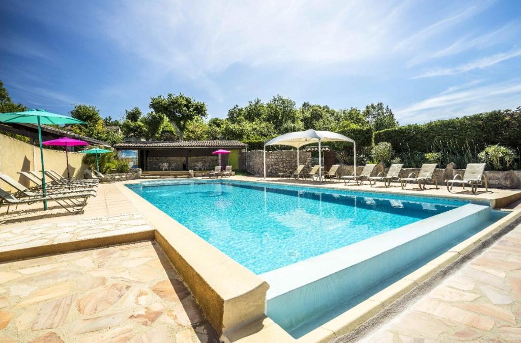ein Pool mit Stühlen und Sonnenschirmen daneben in der Unterkunft Barbouillet - Maison avec piscines partagées in Joyeuse
