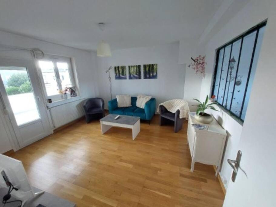 un salon avec un canapé bleu et une table dans l'établissement Apt Nuits au pied du Phare, à Calais